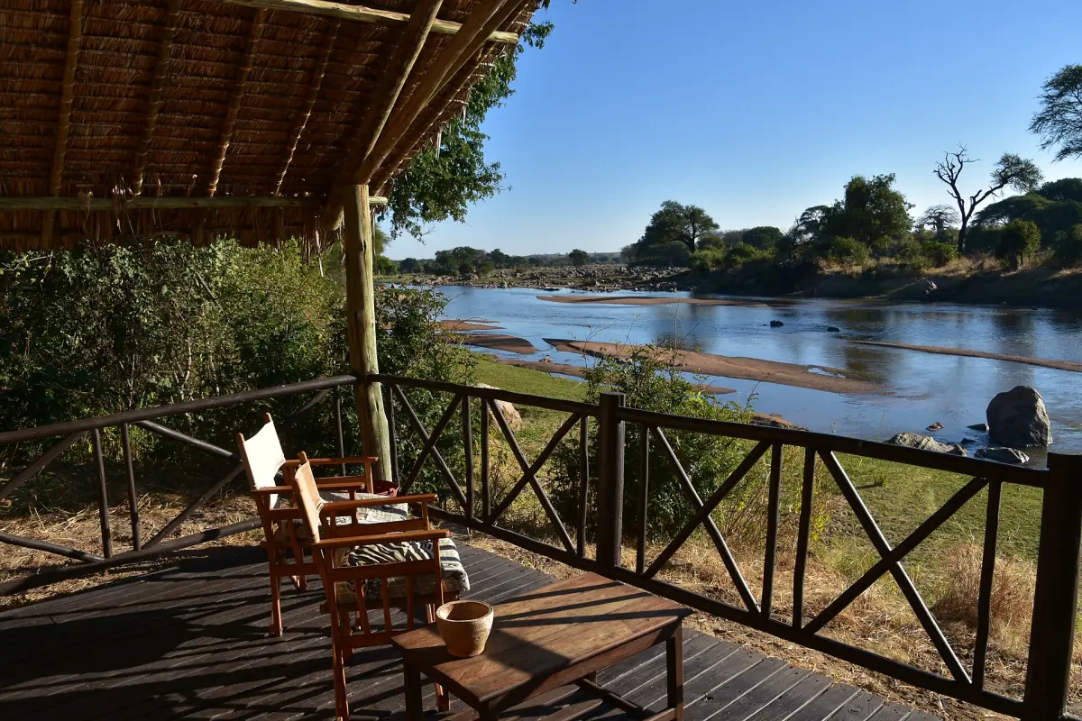 Holzveranda eines Camps mit Stühlen und Blick auf den Ruaha River